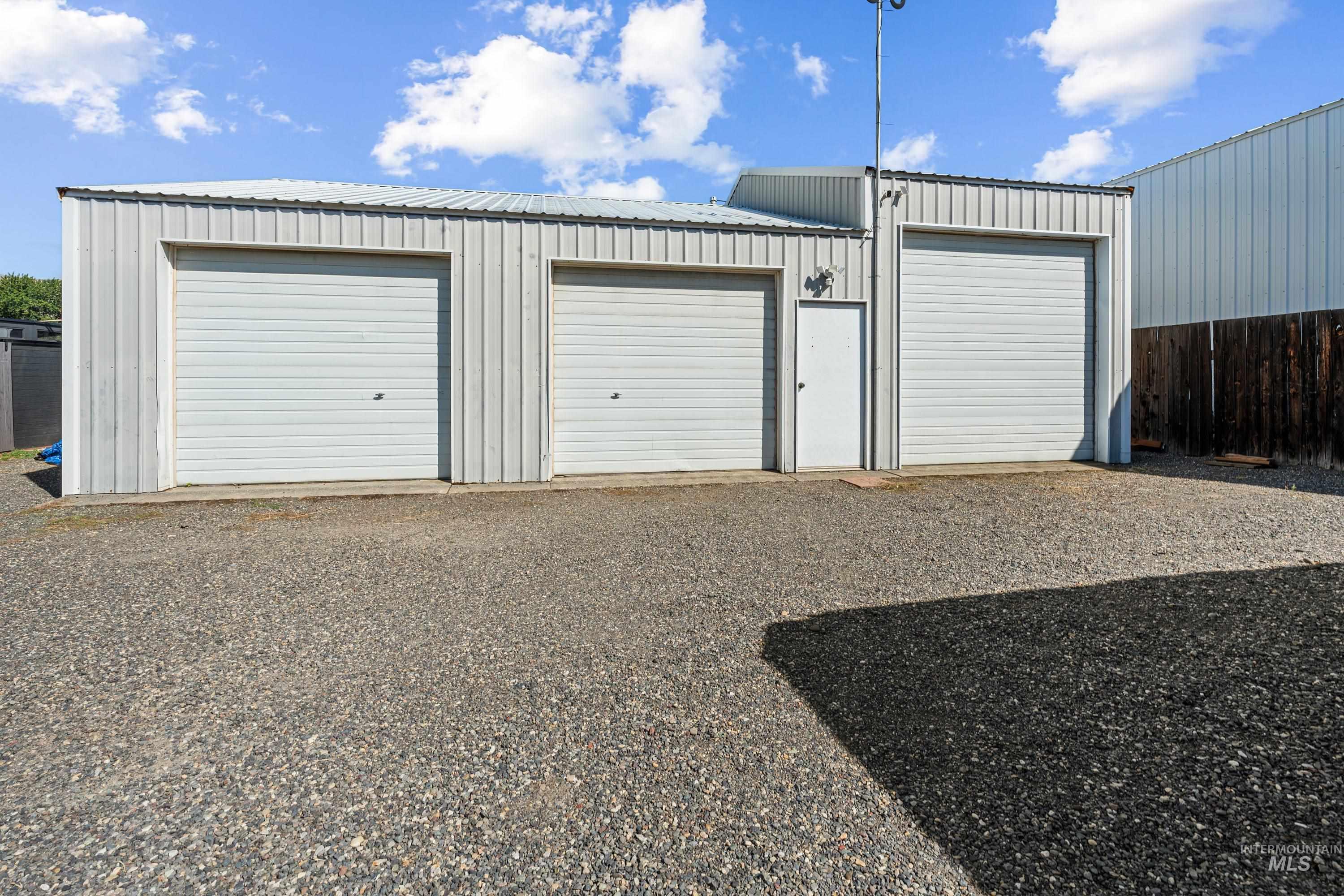 1266 Maple Street Clarkston, WA 99403 - Photo 3 of 44 Corrugated metal exterior with three garage doors and a separate entry door