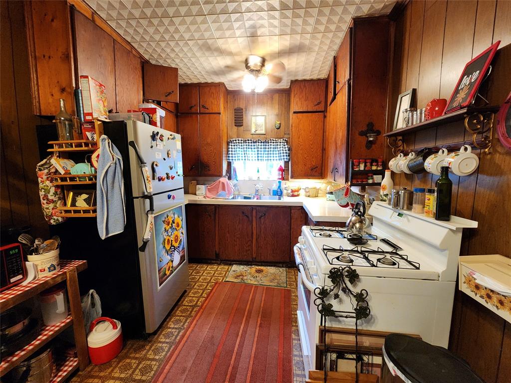 403 Barker Street Cumby, TX 75433 - Photo 3 of 16 Kitchen featuring wood paneling, white countertops, built-in wooden cabinetry, a white gas range, and a patterned ceiling