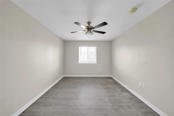 an empty room with a window and a ceiling fan