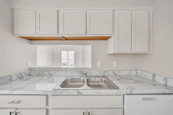 a view with granite countertop a sink and cabinets