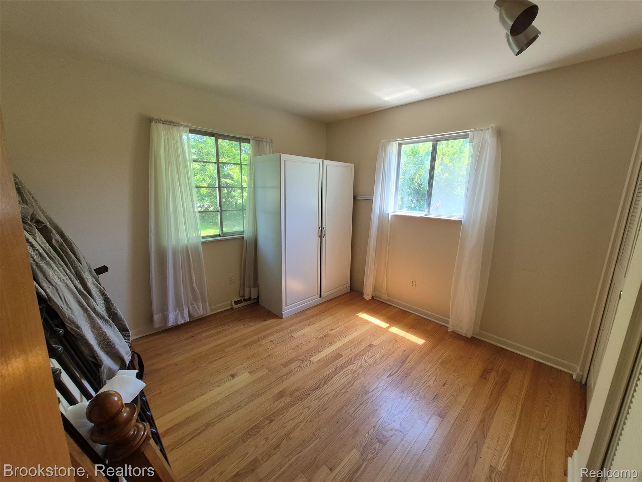 4295 Sashabaw Road Waterford, MI 48329 - Photo 23 of 37 Hardwood flooring complements neutral wall tones in this room featuring two windows