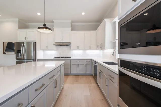 a kitchen with kitchen island a counter top space a sink stainless steel appliances and cabinets