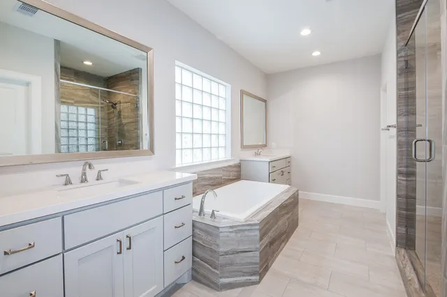 a spacious bathroom with a double vanity sink a mirror and a bathtub