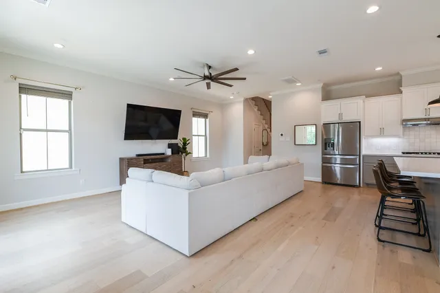 a living room with furniture a flat screen tv and kitchen view