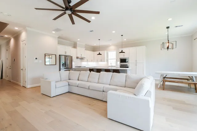 a living room with furniture kitchen view and a chandelier