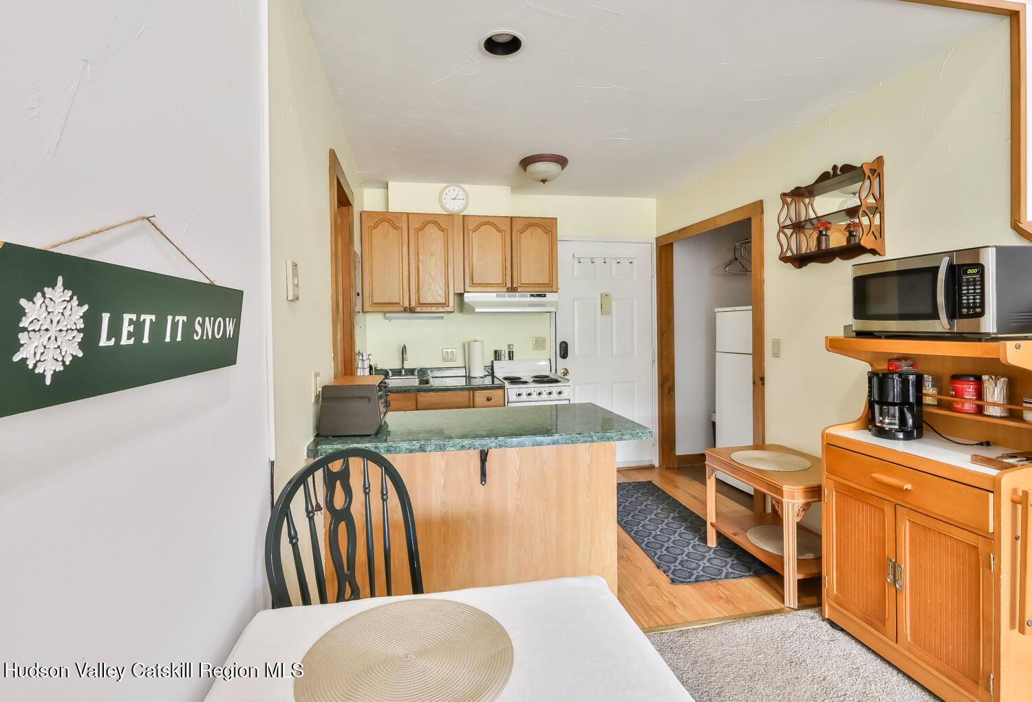 7675 Main Street, Unit B14 Hunter, NY 12442 - Photo 10 of 18 a kitchen with stainless steel appliances kitchen island granite countertop a stove a sink dishwasher and a dining table with wooden floor