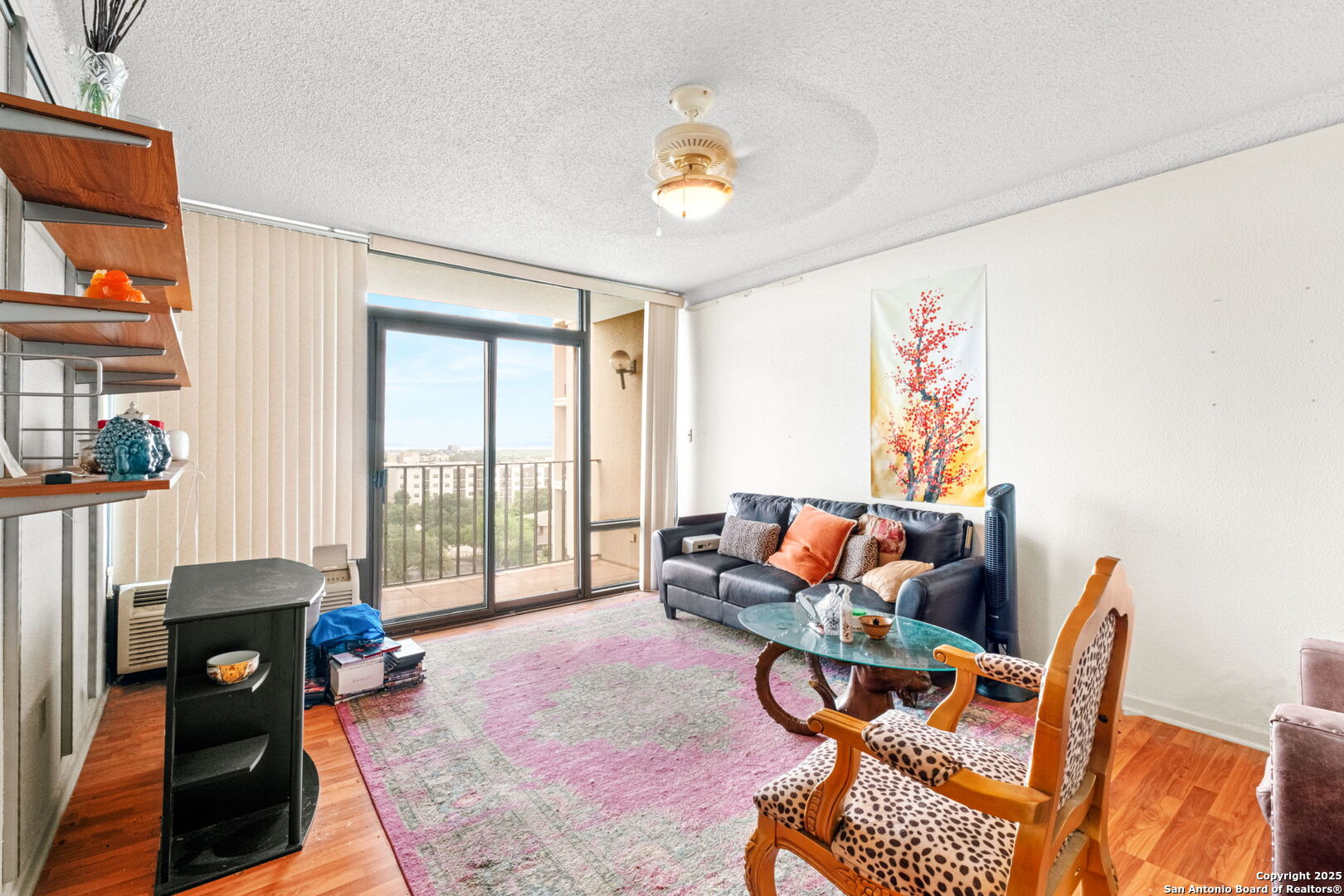 7701 Wurzbach Road, Unit 907 San Antonio, TX 78229 - Photo 11 of 25 a living room with furniture a flat screen tv and a floor to ceiling window