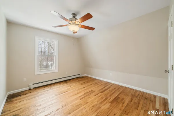 an empty room with wooden floor fan and windows