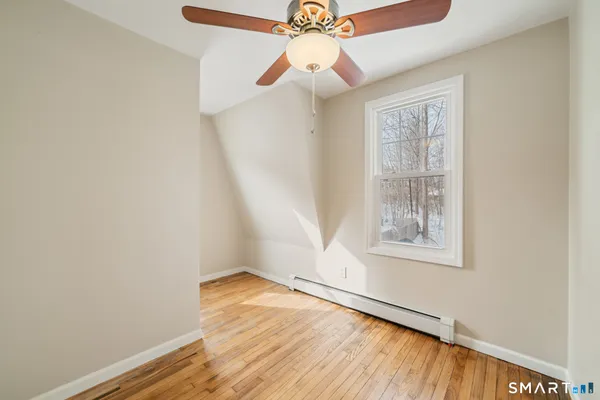 an empty room with wooden floor chandelier fan and windows