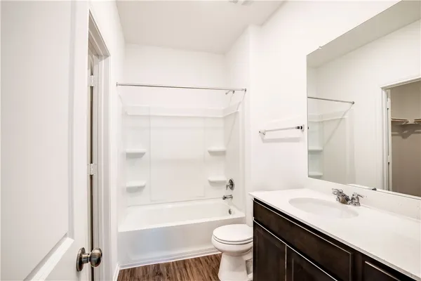 a bathroom with a granite countertop sink toilet mirror and bathtub