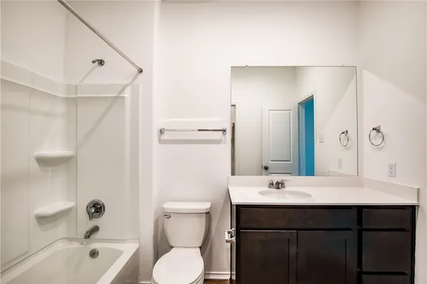 a bathroom with a bathtub shower sink mirror vanity and toilet
