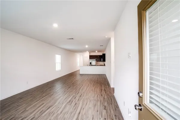 a view of a hallway with wooden floor and a kitchen space