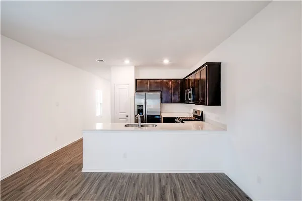 a view of a kitchen with kitchen island a sink wooden floor and counter top space