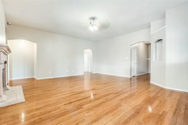 a view of an empty room with wooden floor and a fireplace