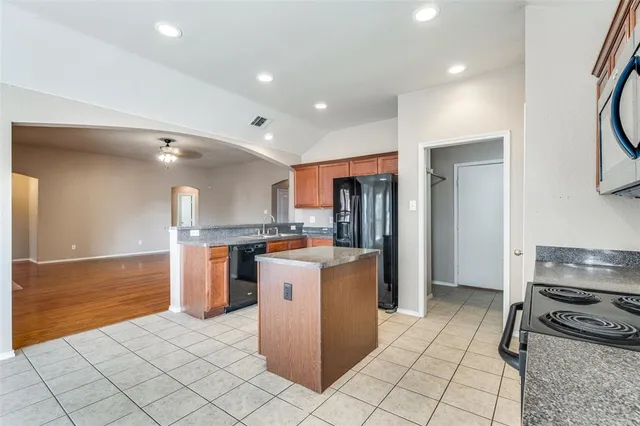 a kitchen with stainless steel appliances kitchen island granite countertop a refrigerator and a stove
