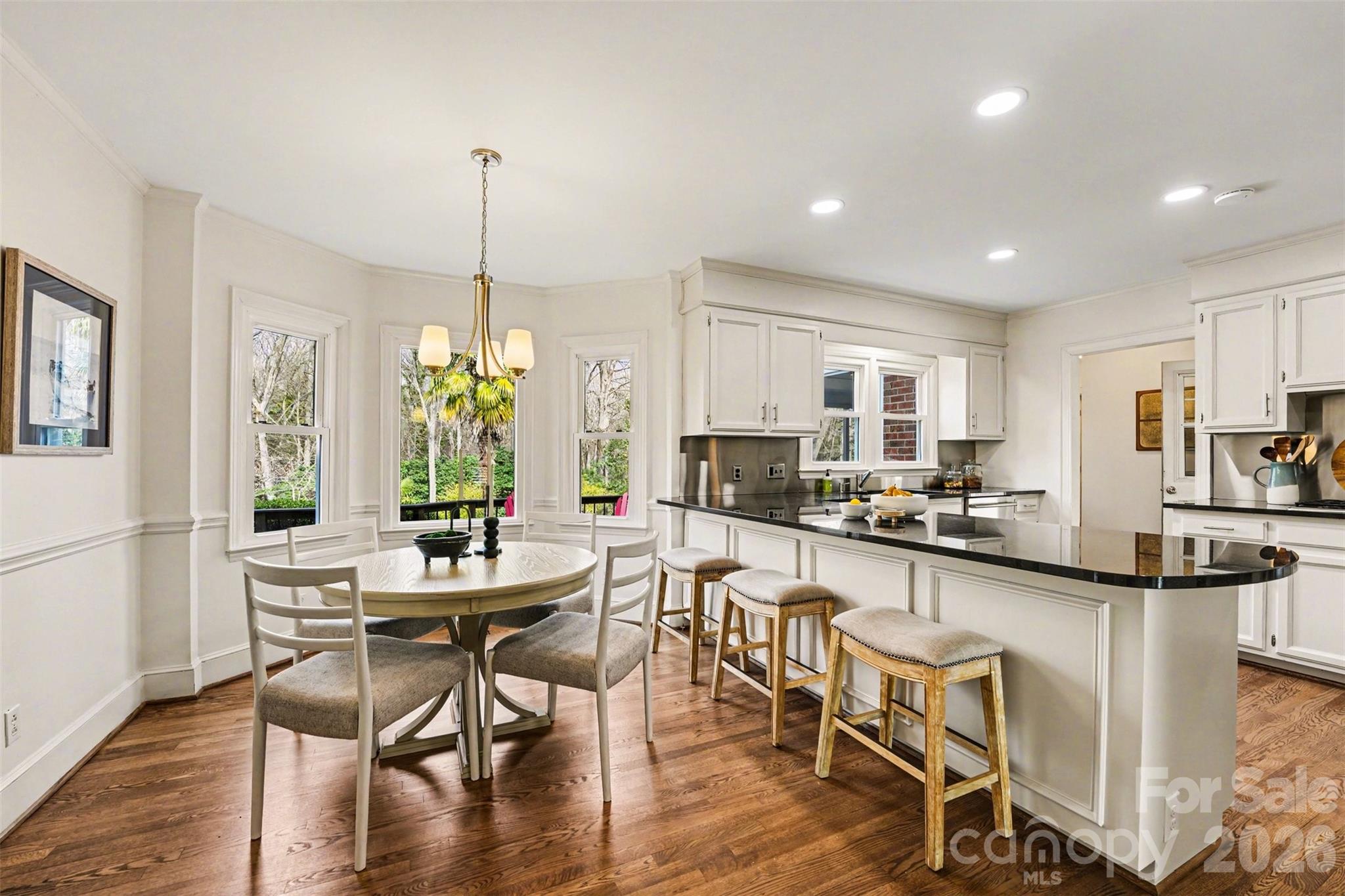 5606 Hillingdon Road Charlotte, NC 28226 - Photo 7 of 41 a kitchen with stainless steel appliances kitchen island granite countertop a dining table chairs and white cabinets