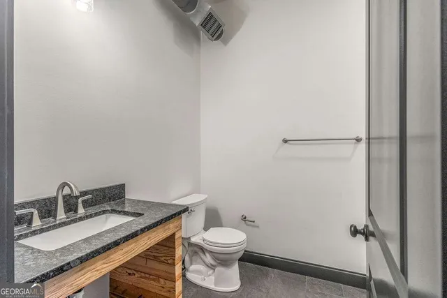 a bathroom with a granite countertop sink toilet and a mirror