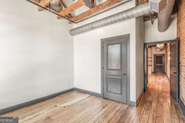 a view of a hallway with wooden floor and a bathroom