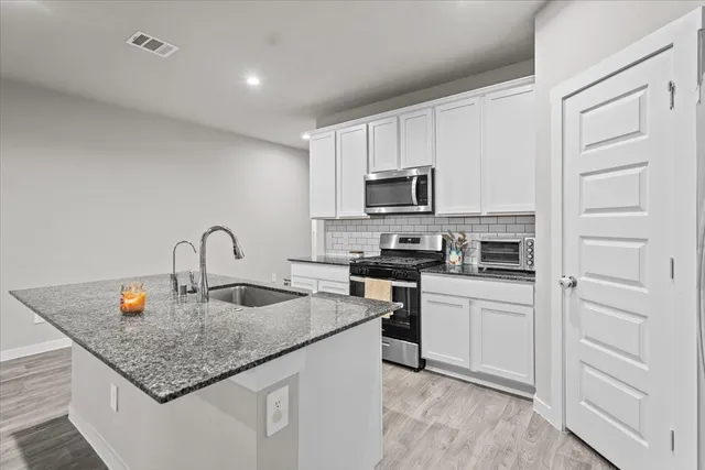a kitchen with stainless steel appliances granite countertop a sink stove and cabinets