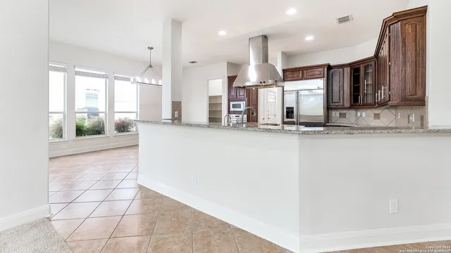 a view of a kitchen with kitchen island granite countertop a large counter top stainless steel appliances and cabinets