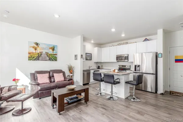 a living room with stainless steel appliances furniture and a kitchen view