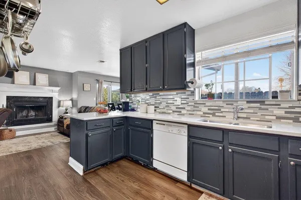 a kitchen with stainless steel appliances granite countertop a refrigerator a sink dishwasher a stove and white countertops with wooden floor