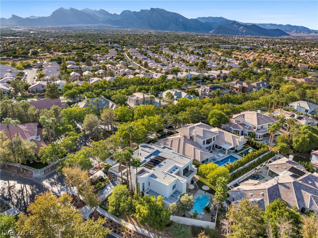 2000 Grouse Street Las Vegas, NV 89134 - Photo 86 of 89 An aerial panorama showcases a neighborhood of luxurious homes nestled among verdant trees with majestic mountains in the distance.