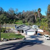 a view of a house with a big yard plants and large trees