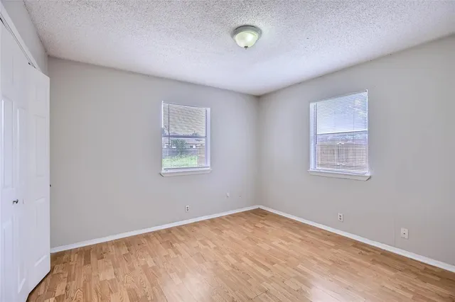 an empty room with a wooden floor and windows