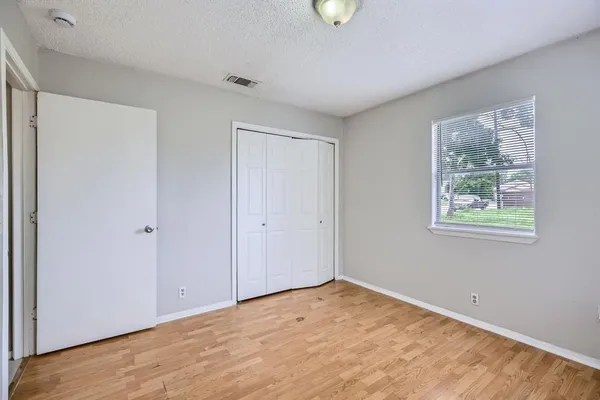a view of an empty room with wooden floor and window