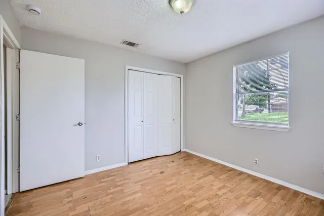 a view of an empty room with wooden floor and window