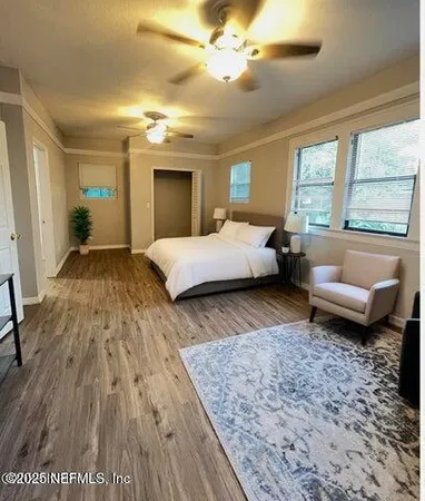 a spacious bedroom with a bed a couch and large window