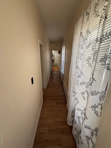 a view of a hallway with wooden floor and a bathroom with a shower