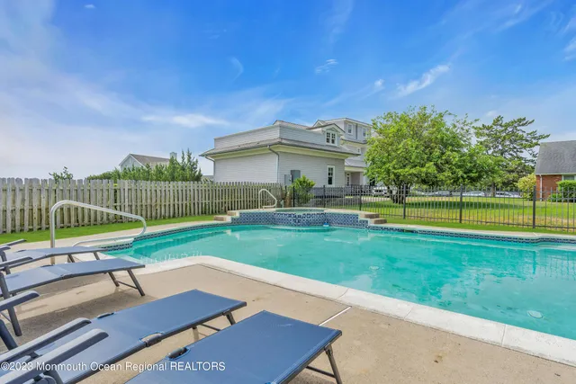 a view of swimming pool with lawn chairs and large trees