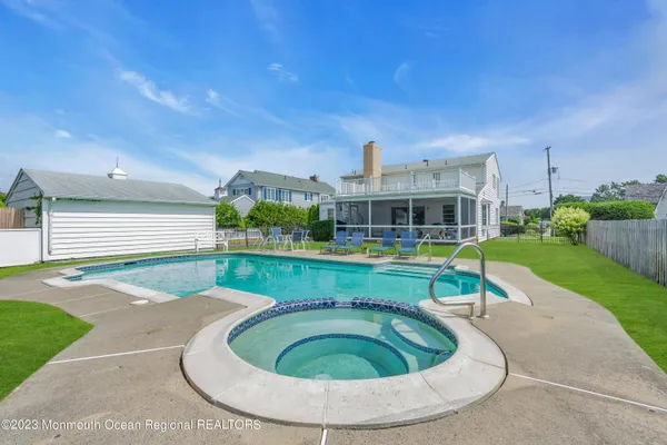 a view of a swimming pool and lounge chairs in back yard of the house