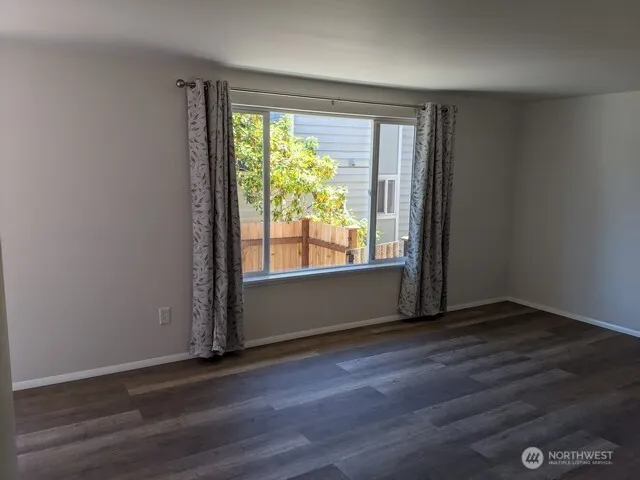 a view of an empty room with a window and a kitchen