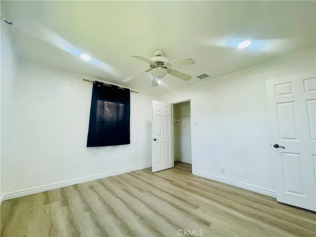 an empty room with wooden floor fan and windows