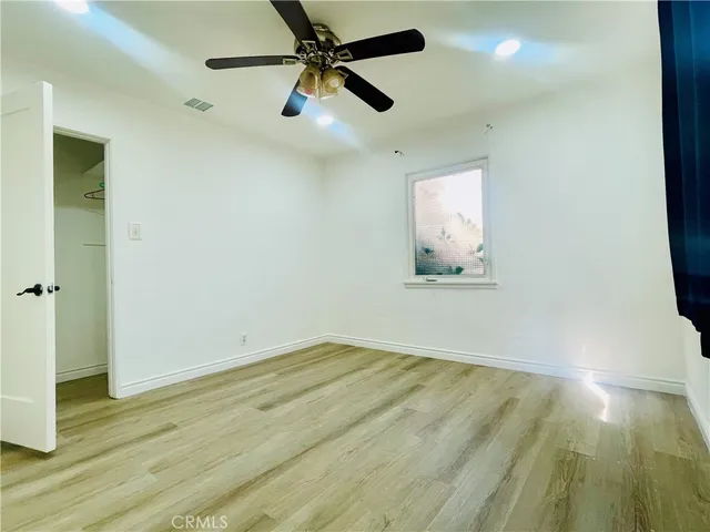 a view of empty room with wooden floor and fan