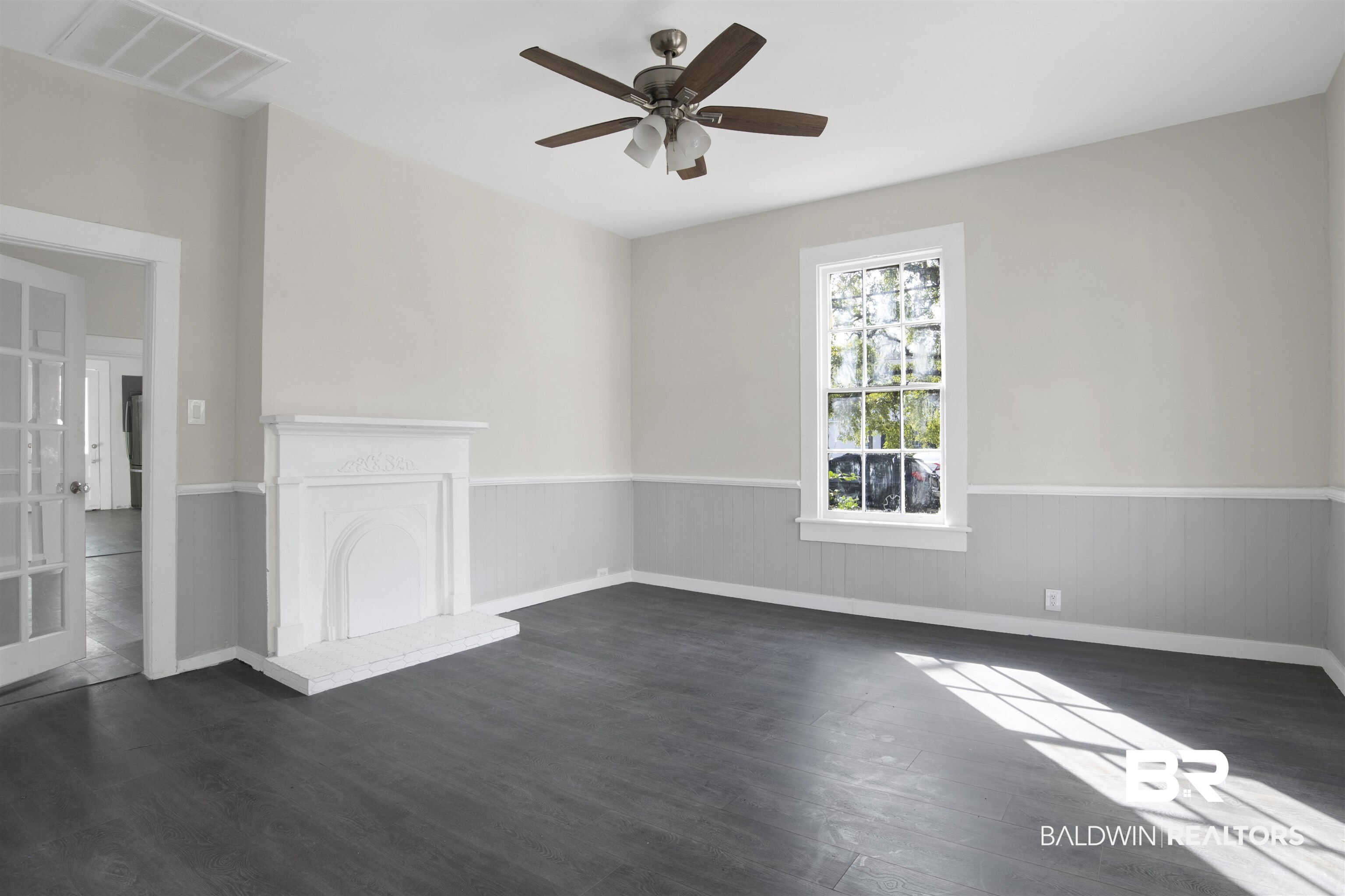 1063 Selma Street Mobile, AL 36604 - Photo 4 of 32 Unfurnished room featuring ceiling fan, dark wood-style floors, wainscoting, and a fireplace with raised hearth