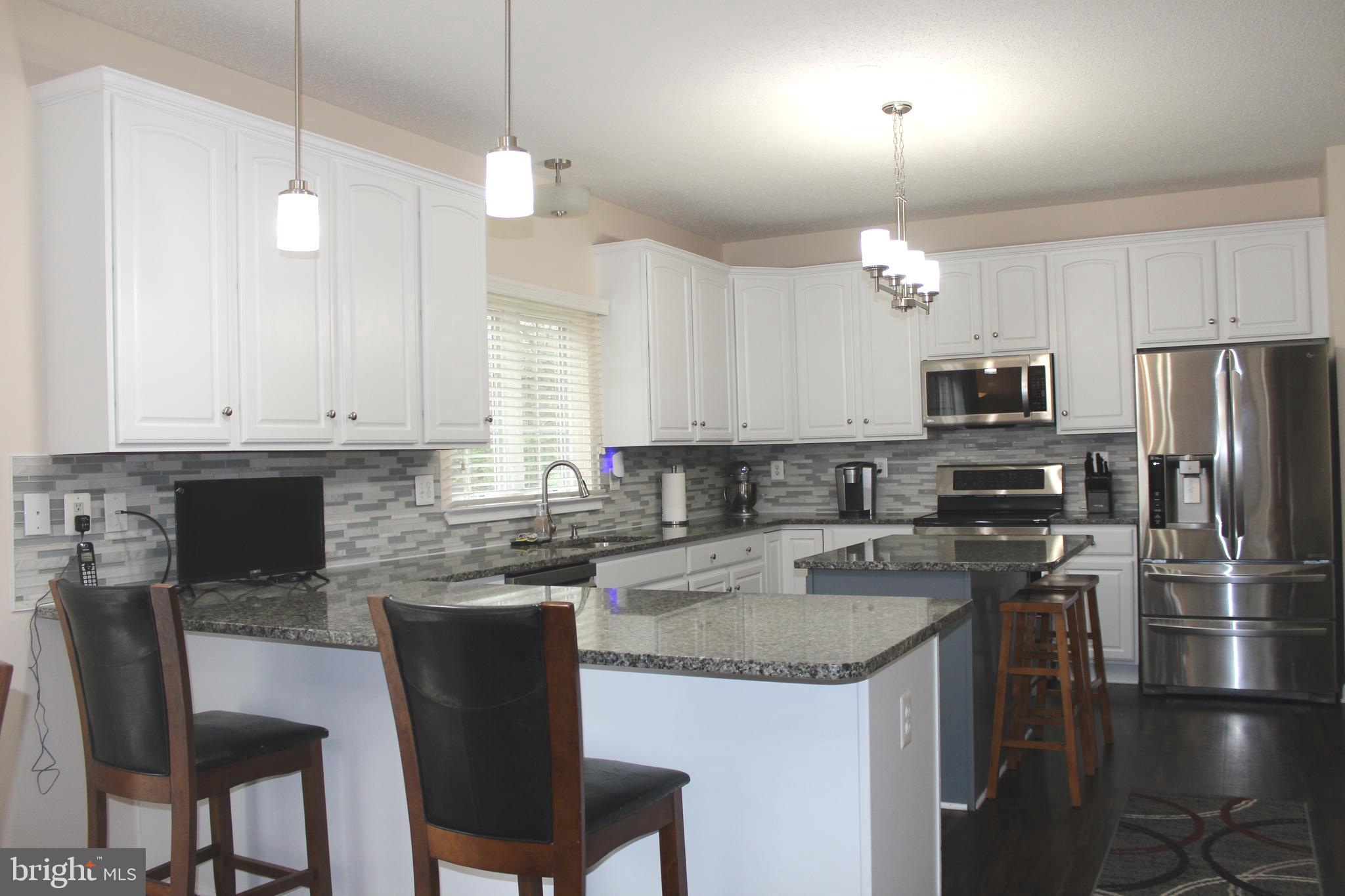 3470 Malcolm Road Brandywine, MD 20613 - Photo 18 of 55 a kitchen with kitchen island granite countertop a table chairs microwave and cabinets