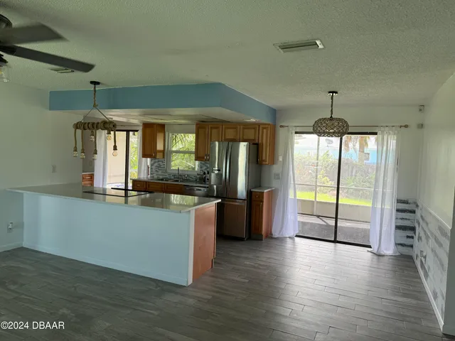 a kitchen with stainless steel appliances granite countertop a refrigerator a oven a stove and a wooden floors