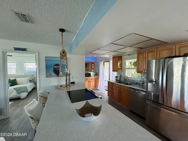 a large open kitchen with stainless steel appliances kitchen island granite countertop a refrigerator a stove and a sink with couches