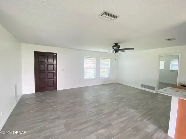an empty room with windows and ceiling fan
