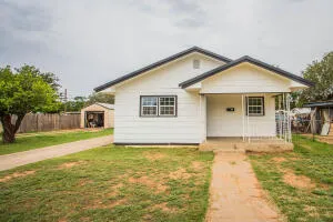 a front view of house with yard and trees in the background