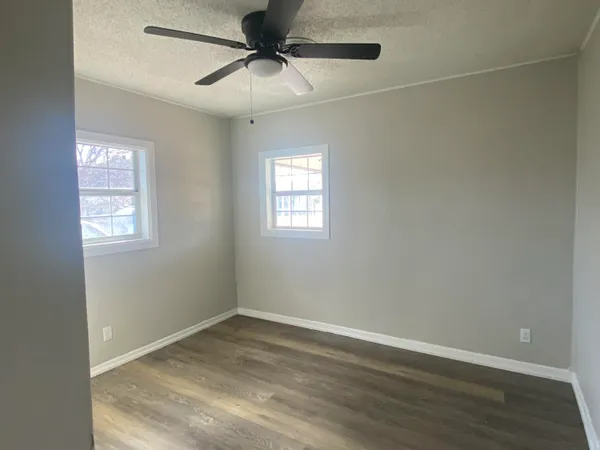 a view of empty room with wooden floor and fan