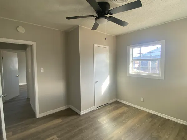 an empty room that has a window and a chandelier fan