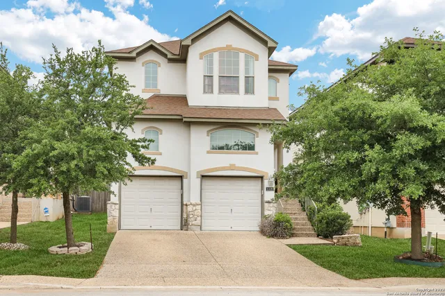 a front view of a house with a garden and trees