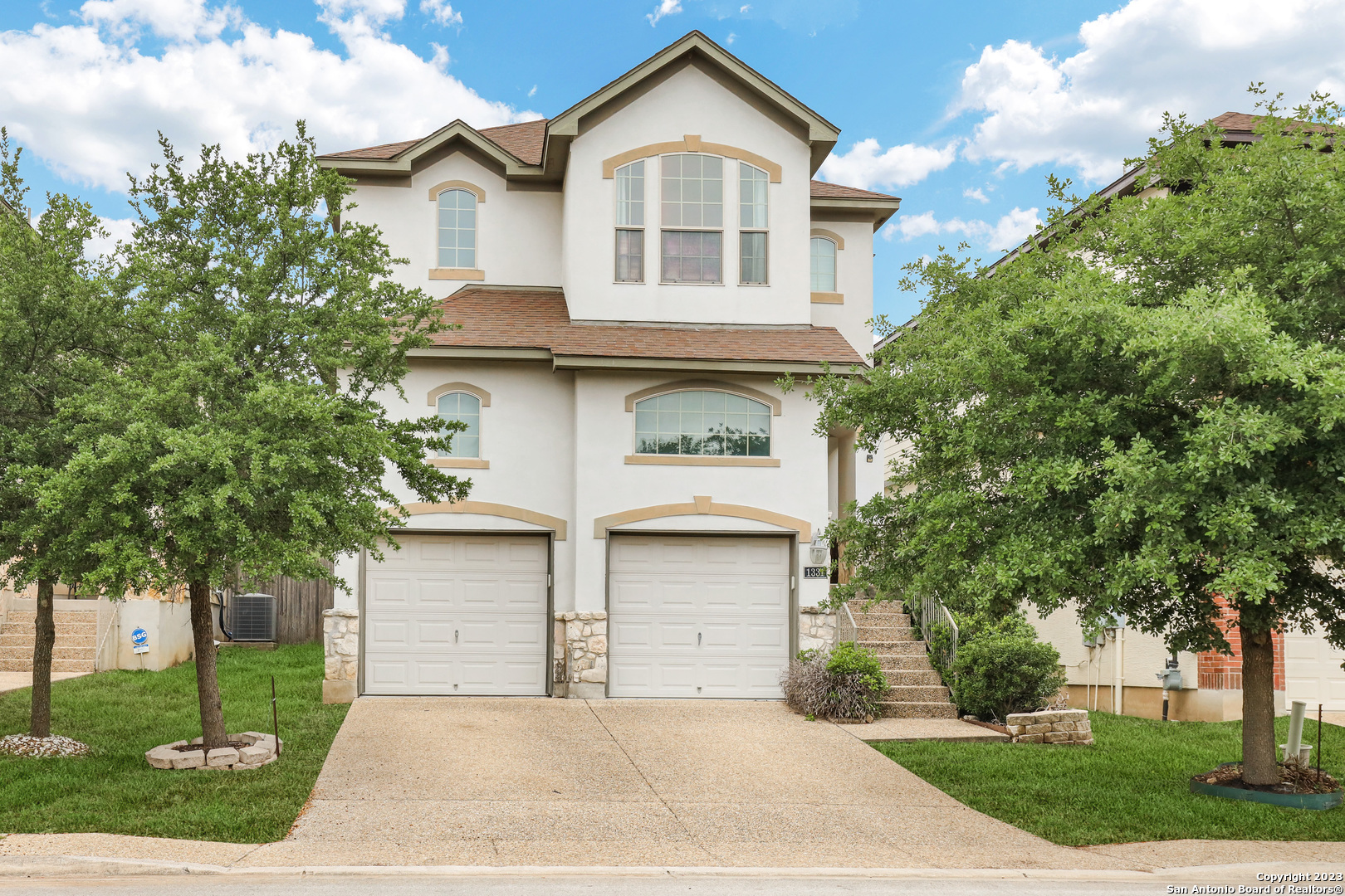 a front view of a house with a garden and trees