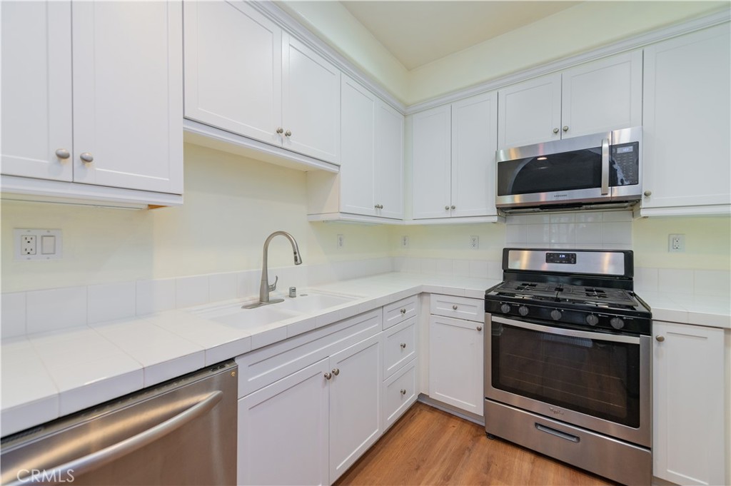 105 Hallmark Irvine, CA 92620 - Photo 7 of 32 a kitchen with white cabinets and black appliances