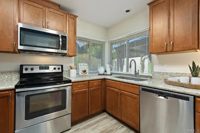 a kitchen with granite countertop a sink stainless steel appliances and cabinets